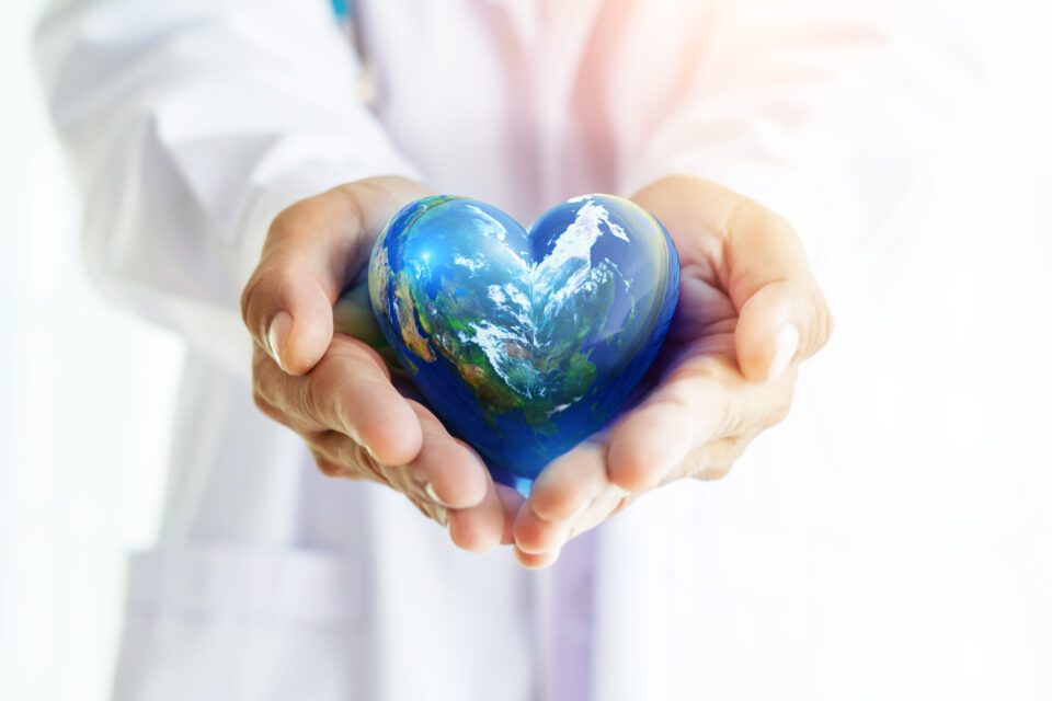 a doctor holds the world in their hands, suggesting that the healthcare industry can work to benefit the world by lowering carbon emissions